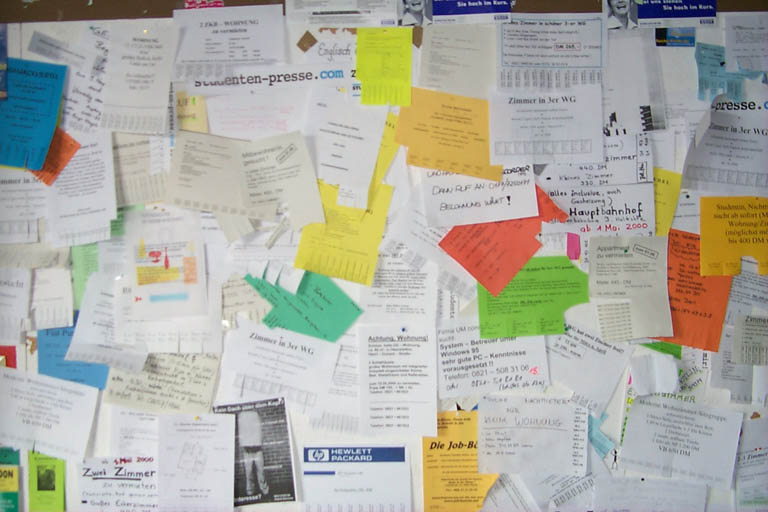 A university notice board covered in adverts